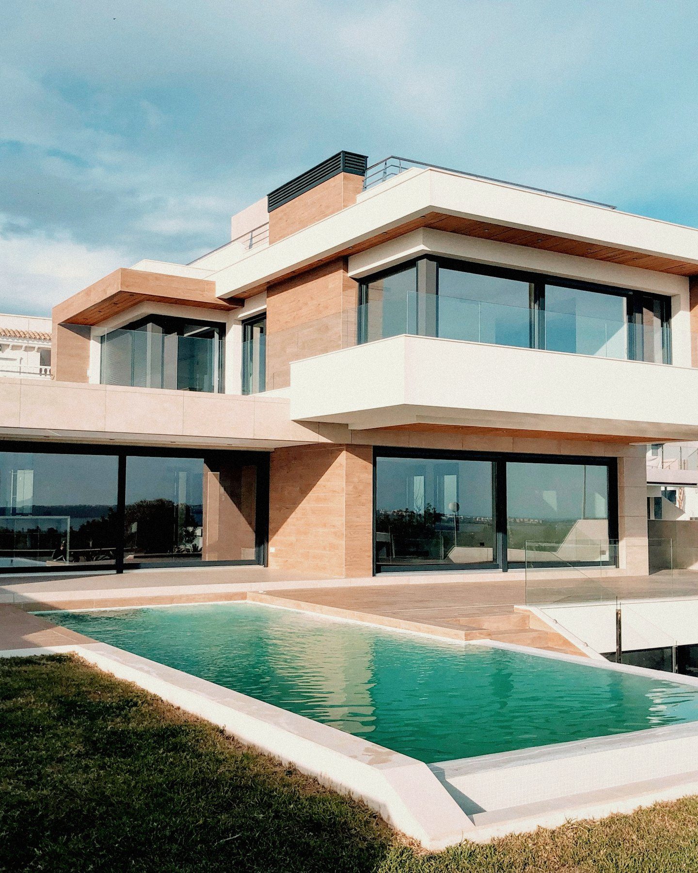 A white modernist villa above the Mediterranean, with a stone terrace and infinity pool at dusk.