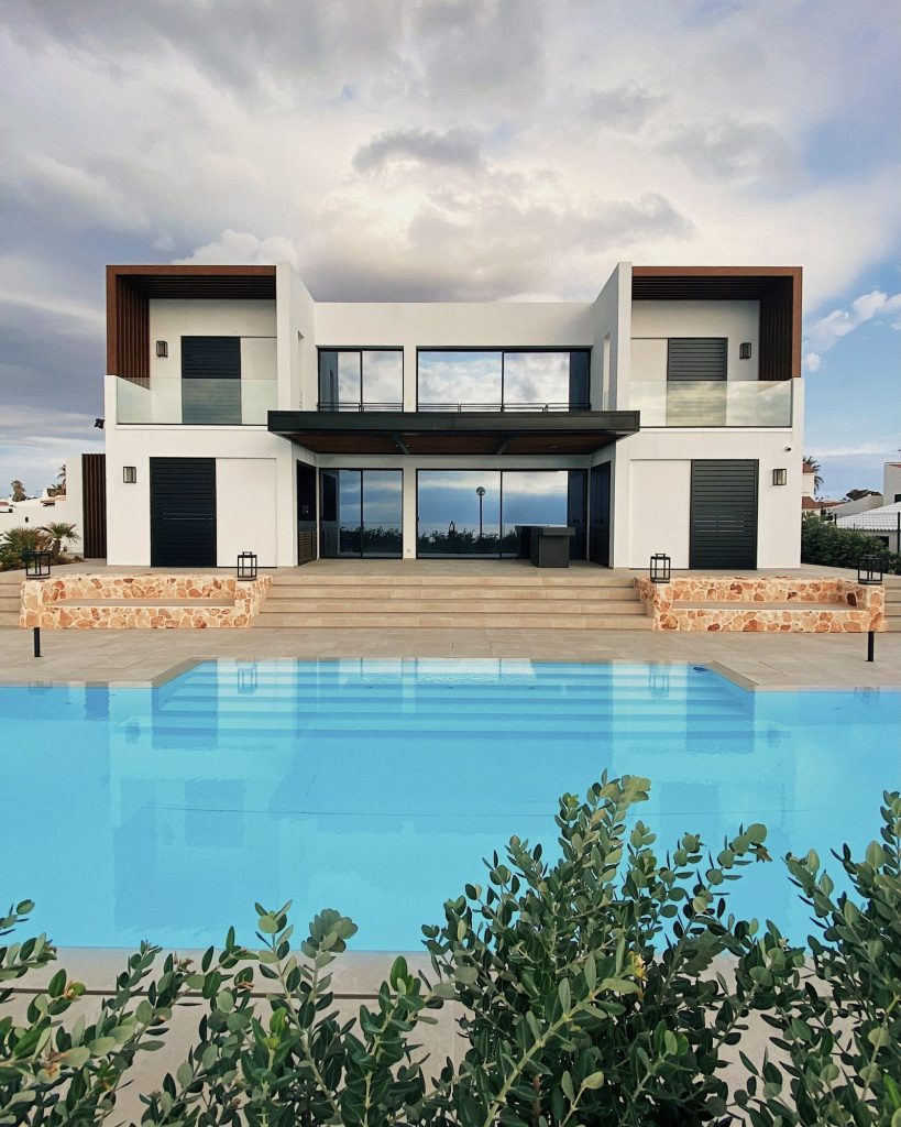 A white modernist villa with stone steps, olive planting and a luminous pool.